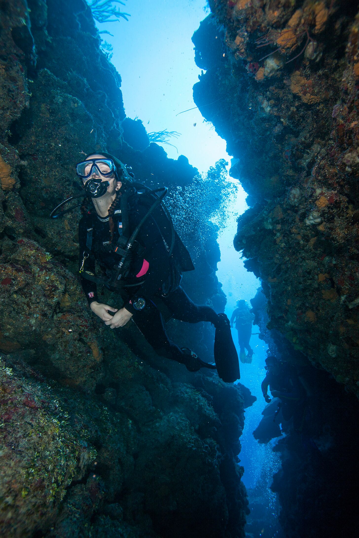 Scuba Diver diving between narrow openings of rocks
